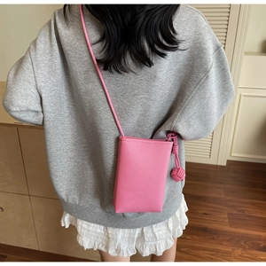Detailed back view of pink lychee leather phone bag with woven knot strap on a model