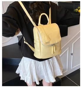 Detail of a creamy yellow leather backpack featuring a handle and double zipper closure