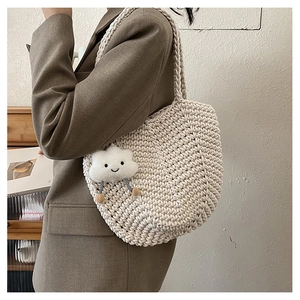 Detail of hollow woven tote bag in cream white with a plush cloud charm accessory