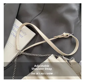 Close-up of adjustable leather shoulder strap and silver metal chain on beige cloud bag