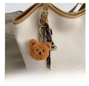 Detail of plush bear charm on white lychee leather tote bag with fashion metal buckle