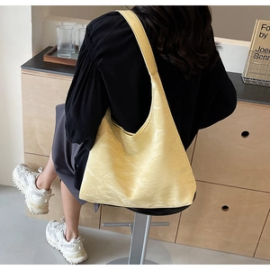 Detailed texture of the yellow ruched nylon tote bag worn as a shoulder underarm bag