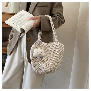 Detail of hollow woven beige tote bag featuring a cute cloud charm and soft cotton texture