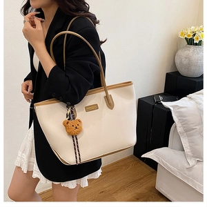 Elegante borsa tote in pelle crema indossata da una modella in un ambiente domestico