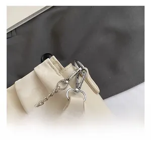 Close-up of polished silver metal hooks and chain on a pleated off-white leather bag