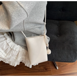Close-up of cream crossbody phone bag with litchi texture and knotted rope strap