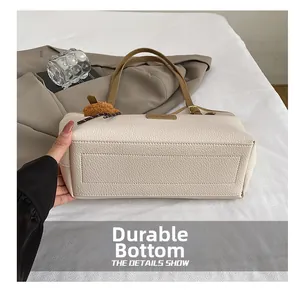 Detail of wear-resistant bottom on beige and brown minimalist tote bag with pebble leather texture