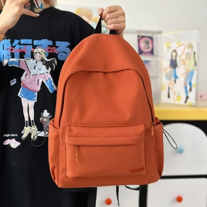 Dettaglio di uno zaino in nylon arancione con tasca frontale con zip e scomparto laterale