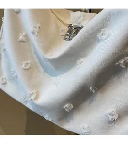 Close-up of white canvas tote bag with textured plush dots and durable metal double zippers