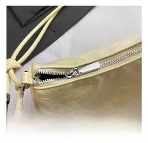 Detail of silver zipper and pleated leather texture on a beige cloud bag