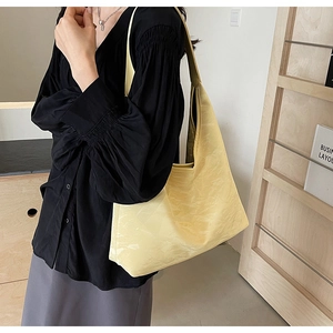 Detail view of large pale yellow tote bag with textured faux leather and wide strap