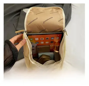 Top view showing large capacity interior of a beige backpack holding iPad and cosmetics