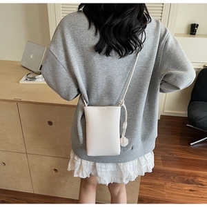 Detail view of cream mini crossbody phone bag with textured lychee grain leather finish