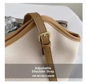 Detail showing adjustable brown leather strap and golden metal buckle on beige tote bag