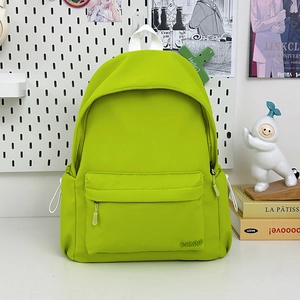 Dettaglio dello zaino in nylon verde neon con tasca frontale zip e logo GDMNC
