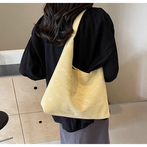 Pale yellow large tote bag with pleated texture shown on shoulder for daily commute style