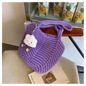 Detail of purple woven tote bag with a cute smiling cloud plush charm on a chair