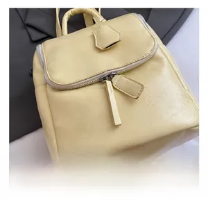Close-up of light yellow litchi texture leather backpack with silver zippers and metal hardware