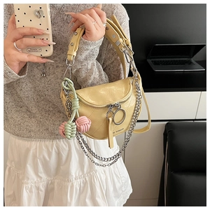 Detail view of yellow leather saddle bag with silver chain straps and cherry charm