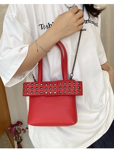 Sac seau rouge en cuir grainé avec nœud à rivets argentés et bandoulière chaîne