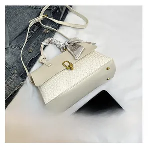Detail view of woven cream handbag with gold lock and silk scarf handle decor