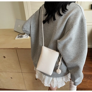 Close-up of a white lychee grain leather mini phone bag with decorative side knot detail