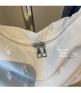 Detailed close-up of premium silver metal zipper pulls on a white canvas tote bag