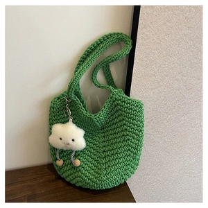 Close-up of green hand-woven tote bag with a cute white plush cloud charm accessory