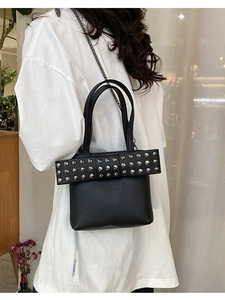 Sac seau noir chic avec nœud en cuir et clous porté par un mannequin en studio