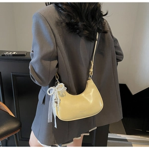 Detail der cremefarbenen Halbmond-Tasche mit Perlenanhänger und Spitzenschleife