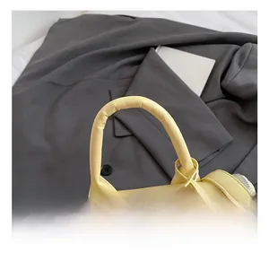 Close-up of the smooth yellow leather handle and zipper on a cylindrical bucket bag