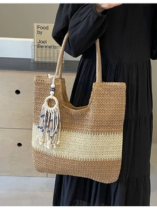 Large woven stripe tote bag with tassel charm and evil eye beads on home background