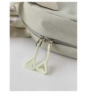 Detail of dual-zipper closure with yellow triangular pullers on beige nylon tote bag