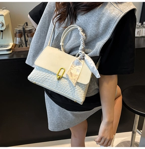 Detail of white leather woven crossbody bag with gold lock and silk scarf handle