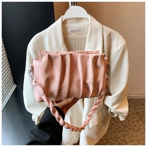 Detail of pink pleated cloud bag featuring woven handle and metallic strap hardware