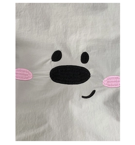 Close-up of cute cartoon animal face embroidery on premium white fabric texture