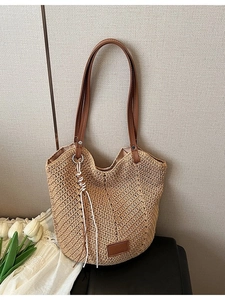 Woven straw tote bag with brown leather handles and tassel for summer vacation style