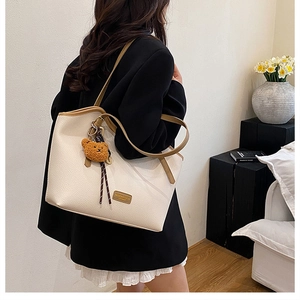 Detail view of large tote bag in beige lychee leather with brown trim and bear charm