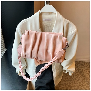Detail of pink pleated crossbody bag with woven shoulder strap and metal hook