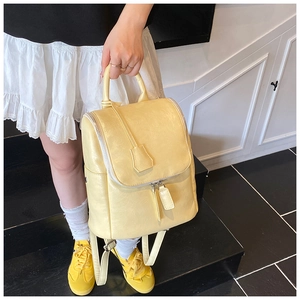 Detail of a creamy yellow leather backpack with smooth zipper and silver hardware accents