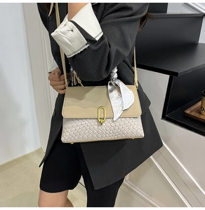 Detail of woven texture handbag with gold oval lock and elegant floral silk scarf accent