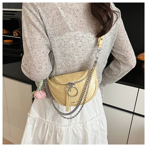 Close-up of cream saddle bag featuring metallic rings and silver chain decoration