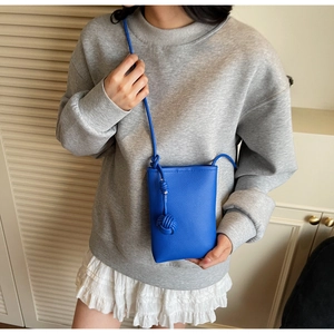 Detail of blue lychee texture leather mini phone bag with decorative knotted leather ball charm