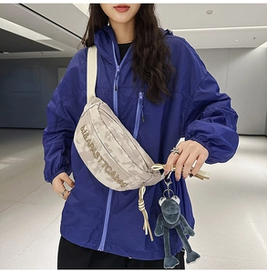 Close-up of beige tie-dye crossbody bag with embroidery and plush frog accessory
