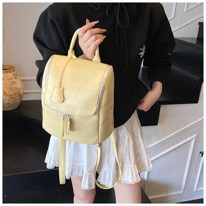 Close-up of a cream yellow PU leather backpack with silver rivets and top handle detail