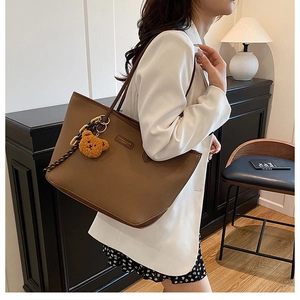 Borsa tote in pelle marrone grana litchi con ciondolo a forma di orsetto giallo