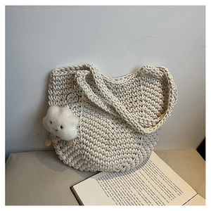 Detail of cream woven tote bag texture with cute cloud pendant on a book background