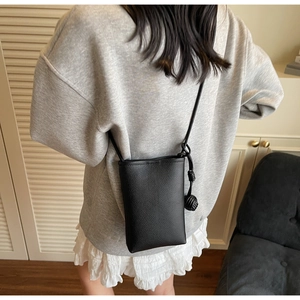 Close-up of a black pebble grain leather mini crossbody phone bag with knot detail