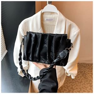 Detail of black pleated shoulder bag with braided strap and silver metal hooks