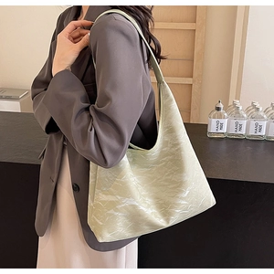 Detail of light green hobo tote bag featuring a pleated leather texture and a spacious design